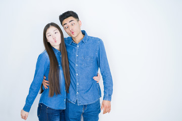 Naklejka premium Beautiful young asian couple over white isolated background making fish face with lips, crazy and comical gesture. Funny expression.