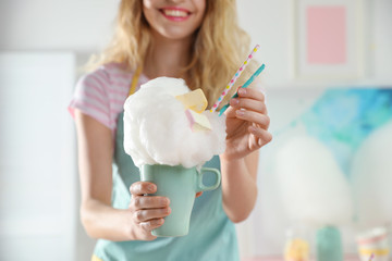 Young woman with cup of cotton candy dessert indoors, closeup