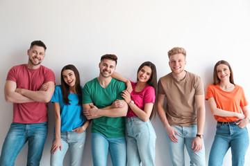 Group of happy people posing near light wall