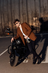 Plakat full length view of man in suit leaning on motorcycle and holding alcohol bottle