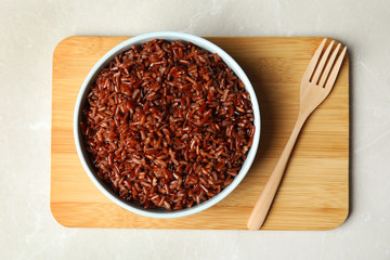 Bowl with delicious cooked brown rice on white marble table, top view