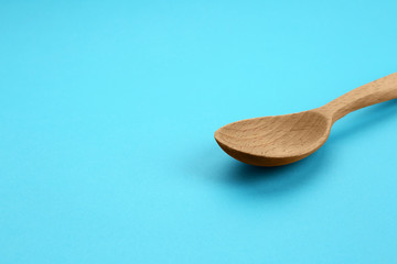 Clean empty wooden spoon on blue background, space for text