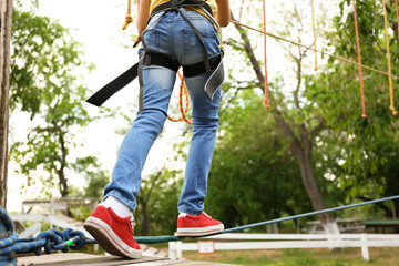 Little girl climbing in adventure park, closeup. Summer camp