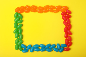 Frame of jelly beans on color background, top view. Space for text