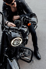 Fototapeta na wymiar high angle view of man sitting on black motorcycle in stylish leather jacket