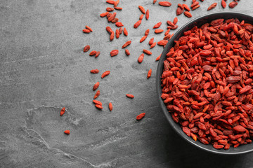 Bowl of dried goji berries on grey table, top view with space for text. Healthy superfood
