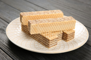 Plate with delicious crispy wafers on wooden table