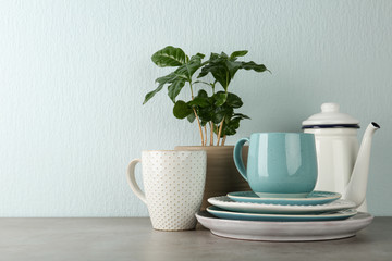 Potted plant and set of kitchenware on grey table near light wall, space for text. Modern interior design