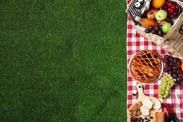 Flat lay composition with picnic basket and products on checkered blanket, space for text