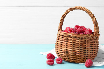 Fototapeta na wymiar Basket of delicious fresh ripe raspberries on blue wooden table against white background, space for text