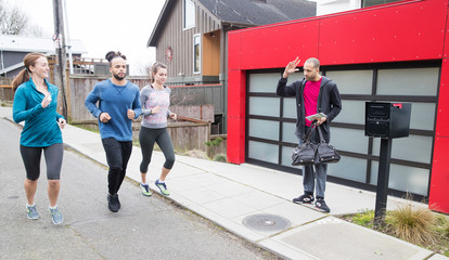 group of people jogging past home where neighbor waves