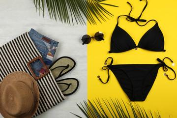 Flat lay composition with black swimsuit and beach accessories on color background