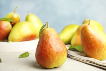 Ripe juicy pears on white stone table against blue background