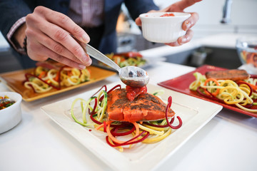 Putting sauce on fresh salmon dinner plate