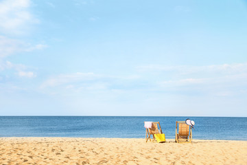 Fototapeta na wymiar Empty wooden sunbeds and beach accessories on sandy shore