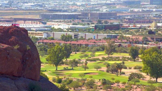 Dramatic Phoenix AZ Overlook from Hikers on a Red Rock towards Scenic Golf Course Green Grass in the Valley below on a Hot and Sunny Day in Arizona