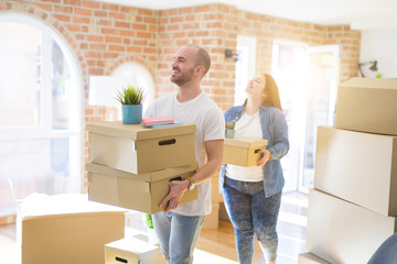 Fototapeta na wymiar Young couple moving to a new home, smiling happy holding cardboard boxes
