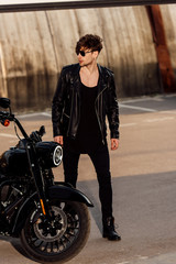 Fototapeta na wymiar full length view of motorcyclist standing near black motorcycle and looking away