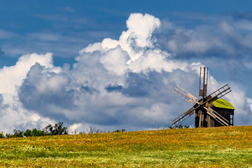 Ancient wooded mill on the background of large clouds on a blue sky. Ukraine.