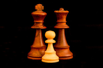 Black King and Queen with white pawn family as interracial adoption concept. Standard chess wooden pieces on black background