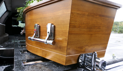 closeup shot of a funeral casket in a hearse or chapel or burial at cemetery