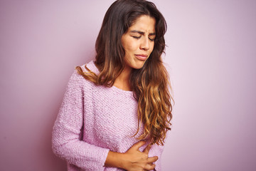 Fototapeta premium Young beautiful woman wearing sweater standing over pink isolated background with hand on stomach because nausea, painful disease feeling unwell. Ache concept.