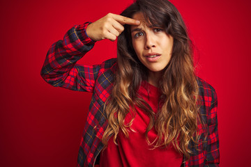 Young beautiful woman wearing casual jacket standing over red isolated background hand on mouth telling secret rumor, whispering malicious talk conversation