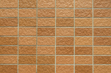Brownish rectangular tiles wall with rough surface as background