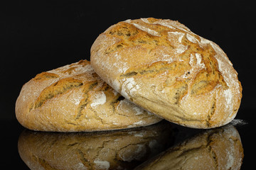 Group of two whole fresh baked rye wheat bread isolated on black glass
