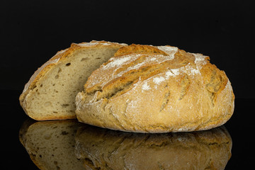 Group of two halves of fresh baked rye wheat bread one sliced isolated on black glass