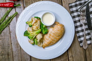 Fried chicken breast with broccoli on wooden table