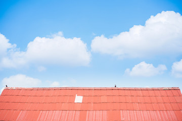 Old roof top built by zinc boards with blue sky and clouds in background.