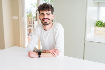 Handsome young man smiling cheerful at the camera with crossed arms and a big smile on face showing teeth