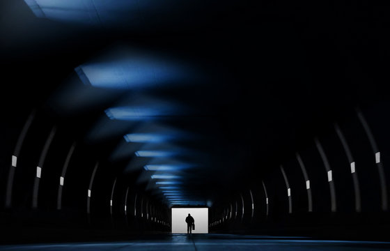 Silhouette of person standing at end of tunnel