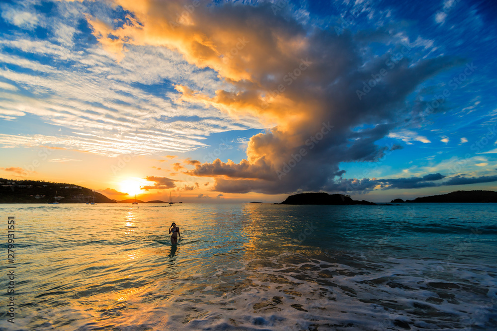 Wall mural beautiful girl wearing a bikini walking out of the ocean at sunset in cinnamon bay, st. john, usvi