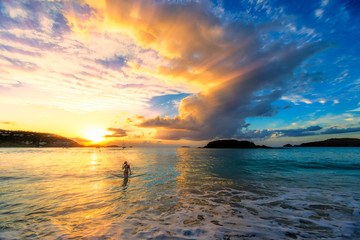 Beautiful girl wearing a bikini walking out of the ocean at sunset in Cinnamon Bay, St. John, USVI