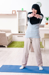 Fototapeta na wymiar Young woman in hijab doing exercises at home