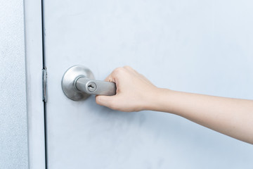 Woman holding a metal door knob close up.  Woman opening the metal door. Metal door knob with key hole.