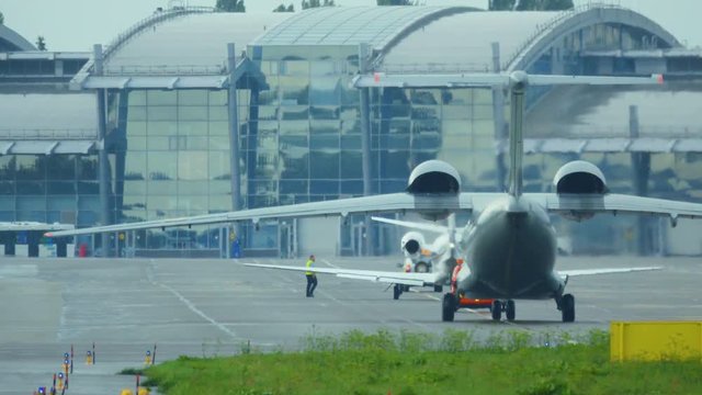 War plane (combat plane) is taxiing on the airfield after landing in rainy weather. Back view
