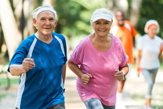 selective focus of cheerful retired couple exercising outside