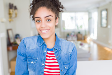 Beautiful young african american woman with afro hair wearing casual denim jacket with a happy and...