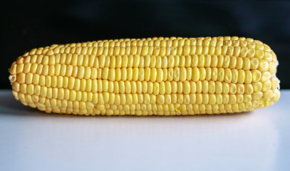 Peeled yellow corn cob on black background.
