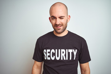 Young safeguard man wearing security uniform over isolated background winking looking at the camera with sexy expression, cheerful and happy face.