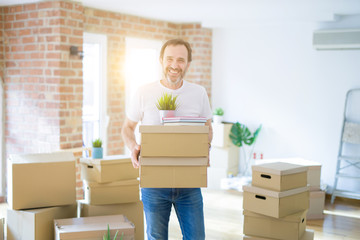 Fototapeta na wymiar Handsome middle age senior man smiling happy moving to a new house, packing and holding cardboard boxes