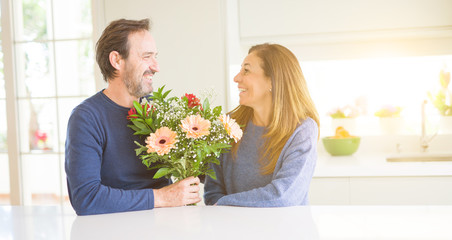 Romantic middle age couple holding flowers in love at home