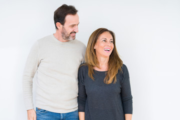 Fototapeta premium Beautiful middle age couple in love over isolated background looking away to side with smile on face, natural expression. Laughing confident.
