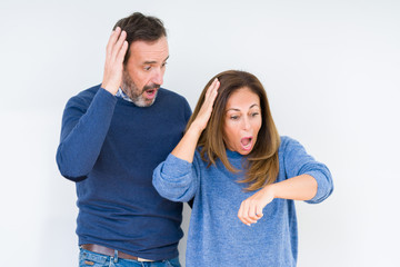 Fototapeta premium Beautiful middle age couple in love over isolated background Looking at the watch time worried, afraid of getting late