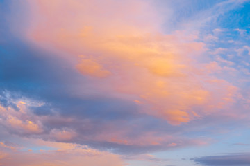 Naklejka na ściany i meble Blue sky with clouds glowing in orange hues at sunset