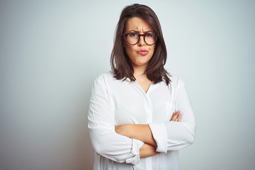 Young beautiful business woman wearing glasses over isolated background skeptic and nervous, disapproving expression on face with crossed arms. Negative person.