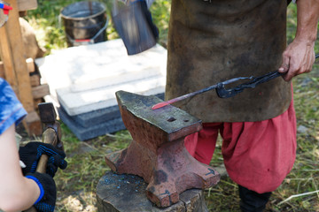 Forge. The blacksmith processes the heated metal with a sledgehammer on the anvil. Manual work of a blacksmith.